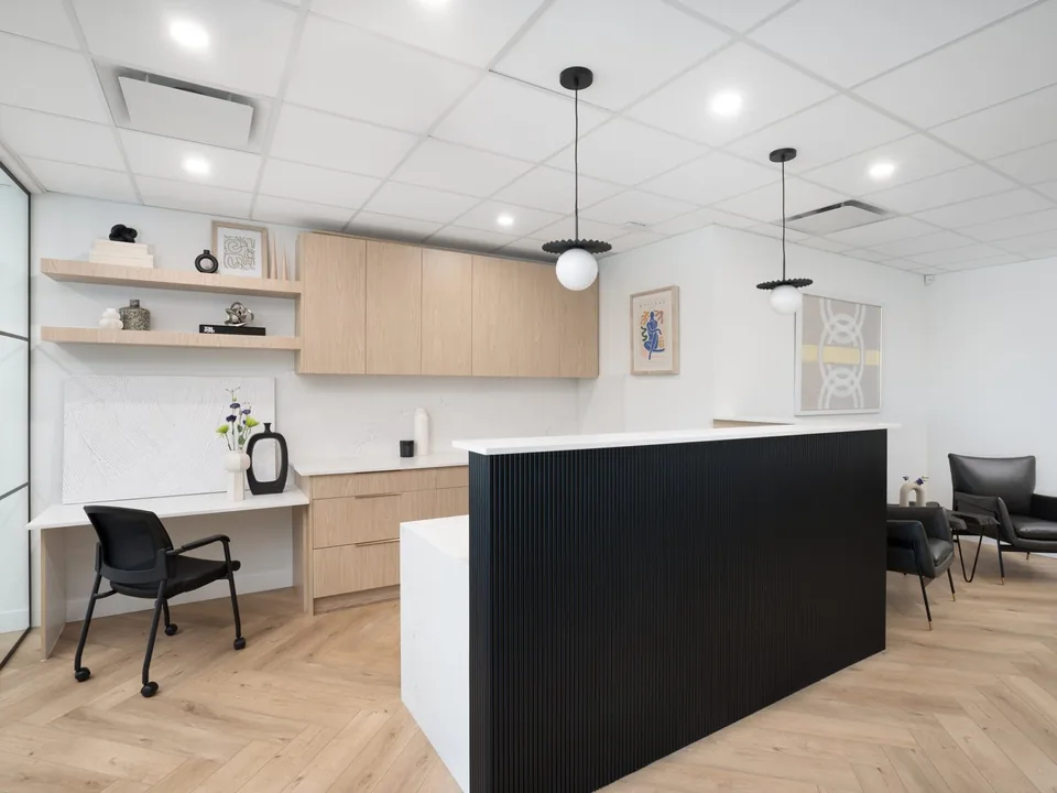 Finished South Surrey office reception with light oak millwork and a black fluted desk
